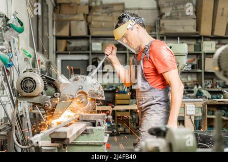 Handyman operating steel cutter machine in workshop Stock Photo