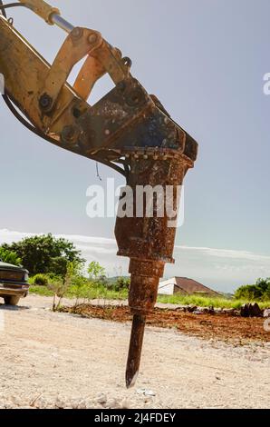 A heavy duty jackhammer attached to the arm of a frontend loader is left suspended. Stock Photo