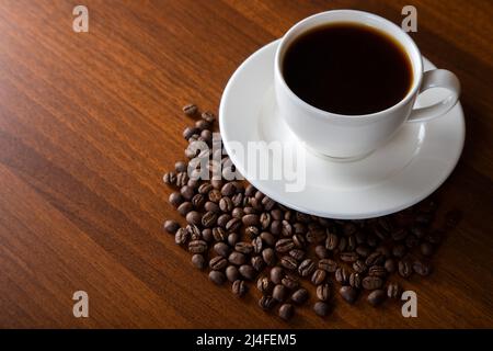 Coffee beans with a cup of coffee on wooden background, top view Stock Photo