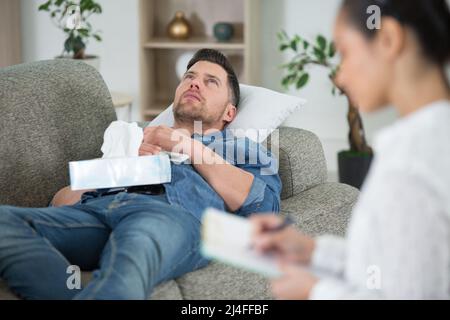 young man at the psychotherapist lying on couch emotionally speaking Stock Photo