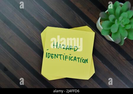 Hazard Identification write on sticky notes isolated on Wooden Table. Stock Photo