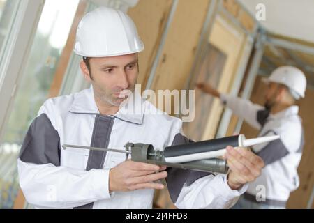 portrait of workers using a silicone gun Stock Photo