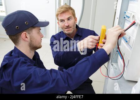 apprentice electrician using a multimeter on a fusebox Stock Photo