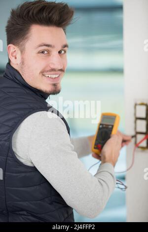 electrician checking socket with multimeter Stock Photo
