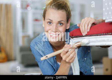 young woman painting an antique chair Stock Photo