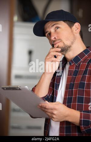 contemplative male inspector holding clipboard Stock Photo