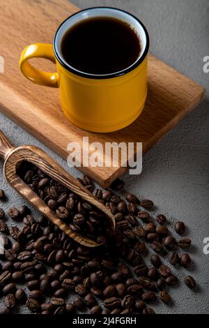 Yellow cup of coffee with coffee beans on concrete background Stock Photo