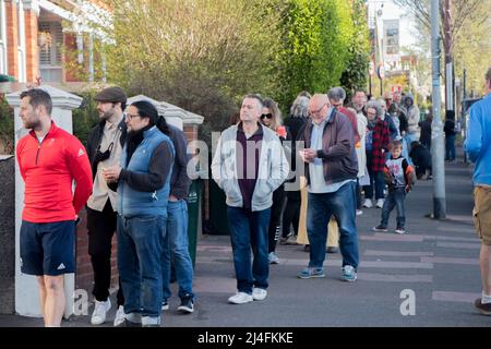 Brighton, East Sussex, UK. 15th Apr 2022. Dozens of people queue for hot cross buns at Brighton Ravens  bakery this Good Friday  The bakery sells thousands of buns every year with customers waiting patiently for more than an hour to get their hands on them.  the bakery opened at 7:30am with a queue of already around 75 people with more joining by the minute,   one lady was taking her buns back to Wales another was handing them out  to friends in Worthing Credit: @Dmoonuk/Alamy Live News Stock Photo