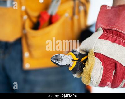 Repairman in protective gloves holding side cutters Stock Photo