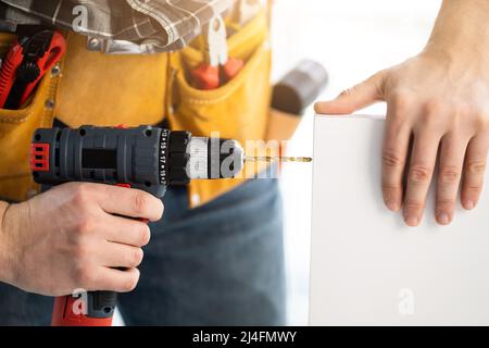 Worker drilling board using mobile drill Stock Photo
