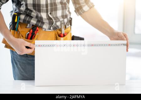Worker measuring furniture board with tape Stock Photo