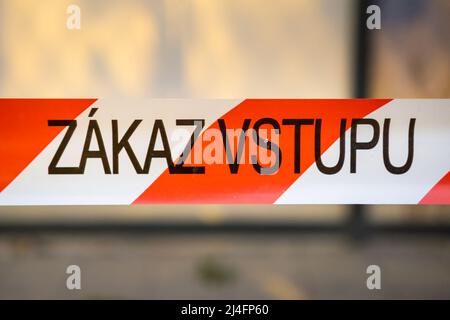 Signal red and white ribbon with Czech inscription Zakaz vstupu forbids entrance to place in city. Warning sign on blurred background closeup Stock Photo