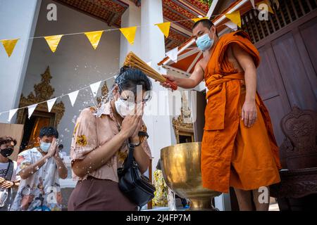 Bangkok, Thailand. 15th Apr, 2022. A monk splashes water on a member of the public in order to give a blessing at Bangkok's Wat Pho temple. Songkran, Thailand's traditional new year celebration which follows the lunar calendar, is normally marked by large street gatherings which turn into massive water fights. Due to the pandemic the last three year's activities have been more subdued. Credit: SOPA Images Limited/Alamy Live News Stock Photo