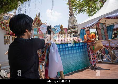 Bangkok, Thailand. 15th Apr, 2022. A woman poses while having her picture taken at Bangkok's Wat Pho temple. Songkran, Thailand's traditional new year celebration which follows the lunar calendar, is normally marked by large street gatherings which turn into massive water fights. Due to the pandemic the last three year's activities have been more subdued. (Photo by Adryel Talamantes/SOPA Images/Sipa USA) Credit: Sipa USA/Alamy Live News Stock Photo