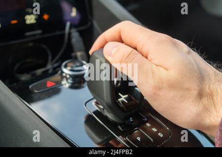 PRAGUE , CZECH REPUBLIC - MARCH 10 2022: Man shifts mode on automatic transmission of new electric car Polestar 2. Luxury modern automobile with stylish interior design closeup Stock Photo