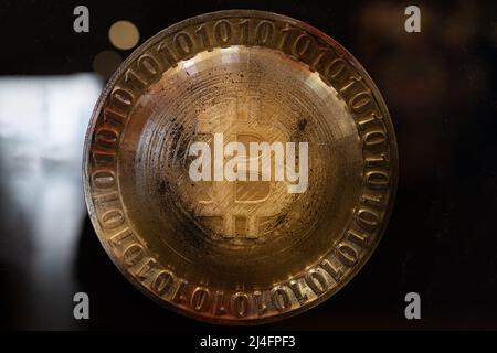 Bitcoin Symbol on a Round Golden Emblem Surrounded by Zeroes and Ones. Stock Photo