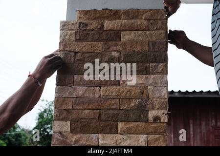 Man working stone tile on new house pole interior building Stock Photo