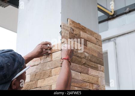 Man working stone tile on new house pole interior building Stock Photo