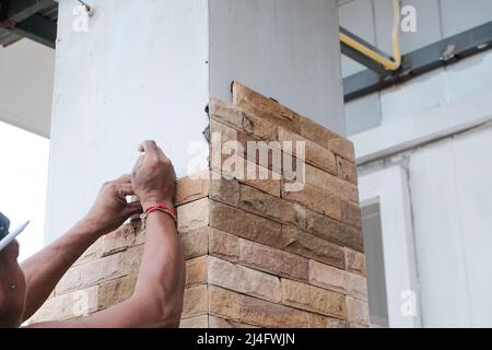 Man working stone tile on new house pole interior building Stock Photo
