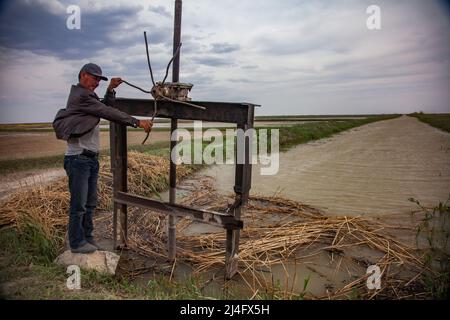 Kyzylorda Province, Kazakhstan - May 01, 2019: Old Soviet hydrotechnic system for paddy field water supplying. Rust screw shutter. Water channel from Stock Photo