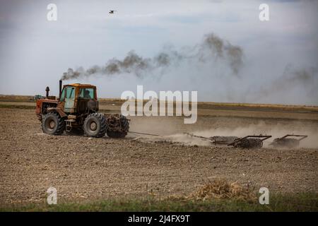 Kyzylorda Province, Kazakhstan - May 01, 2019: Tractor cultivated field soil with plough. Spring sowing season. Stock Photo