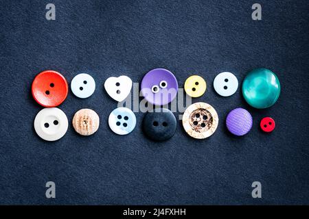 Sewing buttons lying on dark cloth Stock Photo