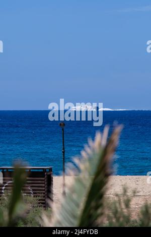 Ios, Greece - May 16, 2021 : A ferry boat passing in front of the famous Mylopotas beach in Ios Greece Stock Photo