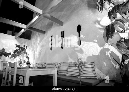 Ios, Greece - June 13, 2021 : View of a beautiful decorated table on an outdoor terrace at night in iOS Greece in black and white Stock Photo