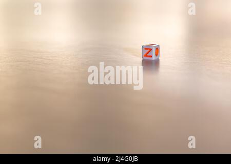 Cube shaped game dice with the orange letter Z on it on a white isolated background. Free text space at the bottom.Generation Z concept. Stock Photo
