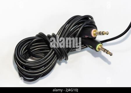 Black cable of microphone and earphone on isolated background. The end of the cable has thin, stereo, male headphone and microphone jacks. Stock Photo