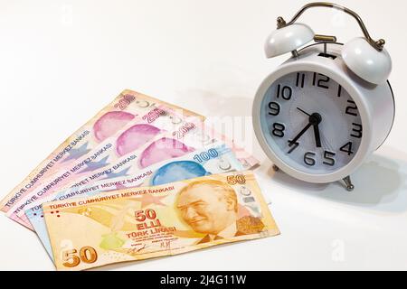 50, 100 and 200 Turkish banknotes and alarm clock on isolated white background. Time is money concept. Stock Photo