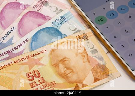 50, 100 and 200 Turkish lira banknotes and calculator app open mobile phone on isolated background. Time is money concept. Stock Photo