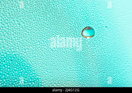 Big and small water droplets on vibrant turquoise background. The large water droplet in the upper right is in selective focus. Bokeh effect. Stock Photo