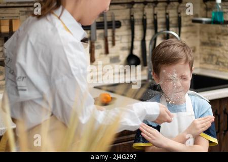 Mom and son in aprons play with flour while cooking at home in the kitchen  against the background of kitchen utensils. Selective focus. Portrait. Clos  Stock Photo - Alamy