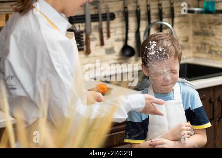 Mom and son in aprons play with flour while cooking at home in the kitchen  against the background of kitchen utensils. Selective focus. Portrait. Clos  Stock Photo - Alamy