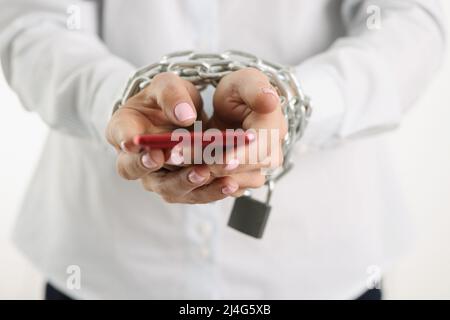 Woman hands tied with chain hold smartphone Stock Photo