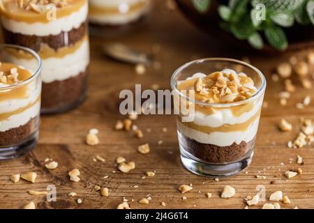 Snickers toffee cream peanut layered dessert in a glass jar on a wooden background Stock Photo