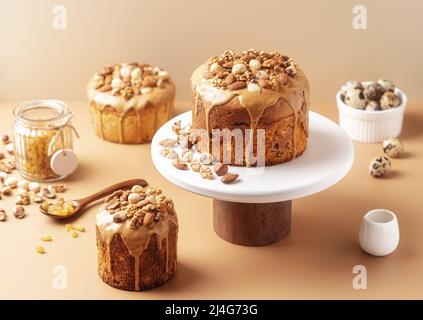 Caramel glazed Easter cakes decorated with nuts on pastel background. Easter composition with cakes, nuts, raisins and quail eggs. Easter background with copy space for your design. Stock Photo