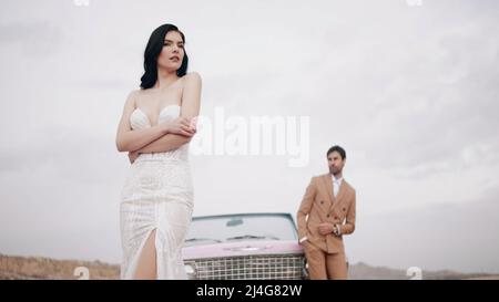 Elegant wedding photo shoot. Action. A beautiful bride in a wedding dress with a groom in a brown suit posing for a photographer on camera with happy Stock Photo