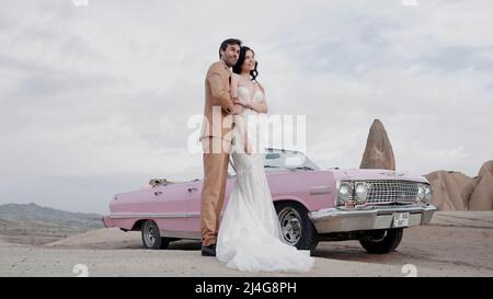 Elegant wedding photo shoot. Action. A beautiful bride in a wedding dress with a groom in a brown suit posing for a photographer on camera with happy Stock Photo