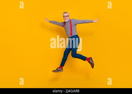 Full size profile side photo of energetic cheerful grandpa enjoy summer vacation isolated on yellow color background Stock Photo