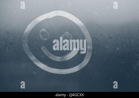 A smiling face painted on the fogged glass.  Stock Photo