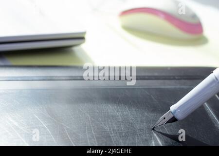 Writing with a fountain pen on a graphic tablet, with scratches on the surface Stock Photo