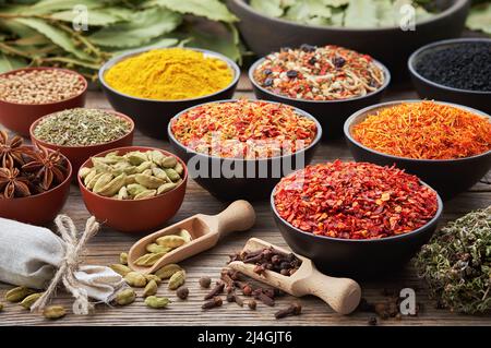 Bowls of various aromatic spices and culinary herbs. Different seasoning - red hot pepper, paprika, anise, saffron, black seeds, nutmegs, cardamom pod Stock Photo