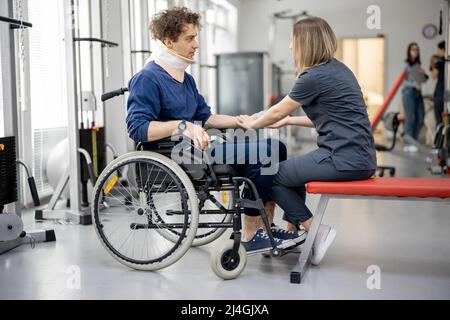 Rehabilitation specialist with guy on a wheelchair doing exercise Stock Photo