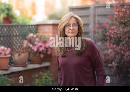 Mature white woman in the garden with flashes of the sun on her back. Stock Photo