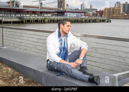 A young student is sitting by a river and into deeply thinking. Stock Photo