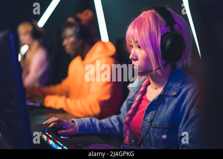 pink-haired Asian young girl playing video games eSport concept medium closeup indoors neon light. High quality photo Stock Photo