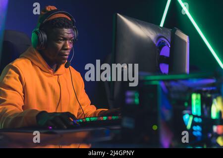 African American man playing online video games tournament medium closeup game battles neon light indoors. High quality photo Stock Photo