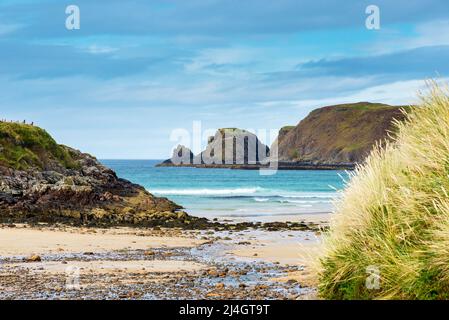 Sparkling white surf contrasts with the blue sea as waves break on the sandy beach at Farr bay. Stock Photo